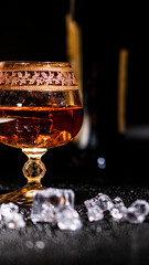 Glass with cognac and ice on a dark background. the concept of alcoholism and drinking