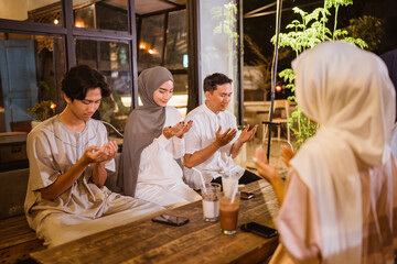 Group of Muslim friends praying before enjoying an outdoor iftar dinner