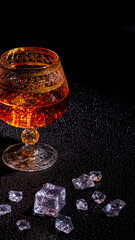 Glass with cognac and ice on a dark background. the concept of alcoholism and drinking