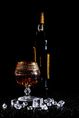 Glass with cognac and ice on a dark background. the concept of alcoholism and drinking