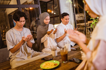praying together, a group of Muslim friends pray before enjoying an outdoor dinner