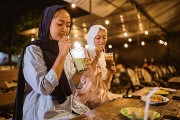 veiled Muslim woman drinks before eating while breaking fast together at a restaurant