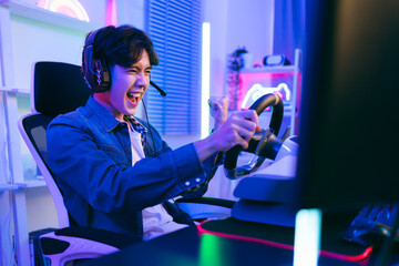 Portrait of Asian male gamer celebrating victory in front of the gaming table. Gamer winning an esports game with victory emotion. The player rejoices in victory in the competition. © artitwpd