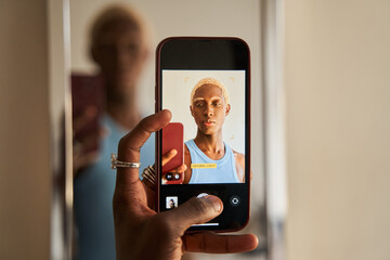 Dark skinned blonde fashionable guy making smartphone selfie
