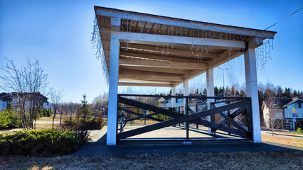 Beautiful Wooden gazebo outdoor on a Sunny autumn or spring day with blue sky. Early sprint time and pavilion or alcove in village or small town on nature landscape