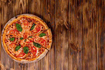 Delicious fragrant pizza-Margherita with mozzarella, tomatoes and basil on tomato sauce on woden background. Copy space