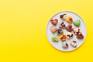 Plate with different chocolate on colored background. Assortment of fine chocolates top view vith copy space Health and obesity concept
