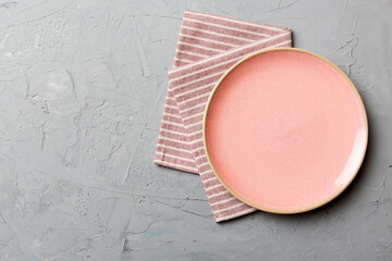 Top view on colored background empty round pink plate on tablecloth for food. Empty dish on napkin with space for your design