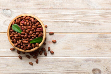 Fresh healthy peanuts in bowl on colored table background. Top view Healthy eating bertholletia concept. Super foods