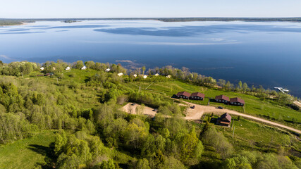 Fototapeta na wymiar panoramic aerial view of the lake and the green meadow with buildings taken from a drone in summer