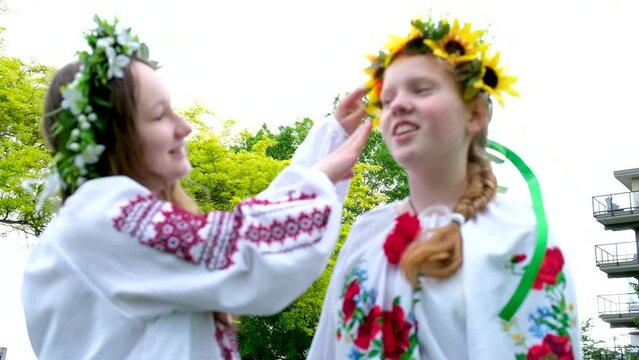 beautiful young women girls weaving wreaths walking laughing chatting in park in garden embroidered national ukrainian shirts wreaths of sunflower flowers and forest white 