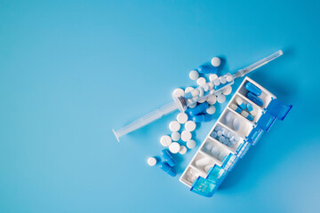 Blue-white pills and capsules in weekly pill organizer