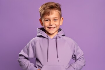 Portrait of a cheerful little boy in a purple hoodie on a purple background
