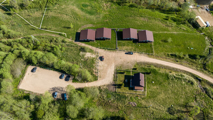 panoramic aerial view of the lake and the green meadow with buildings taken from a drone in summer