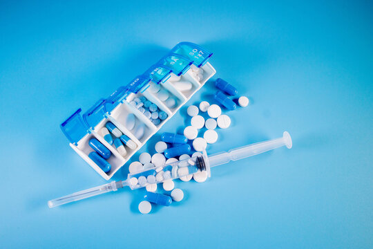 Top View Of Weekly Pill Box Organizer, Portable Travel Prescription Or Medication Pill Case On Blue Background. Healthcare And Medical Concept.