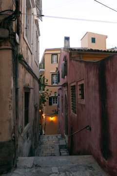 Cosy narrow street with pink and yellow buildingsin Corfu old town, Greece
