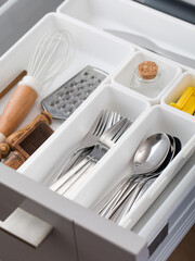  Organizer trays with a set of cutlery in a drawer in the kitchen. Storage system concept.
