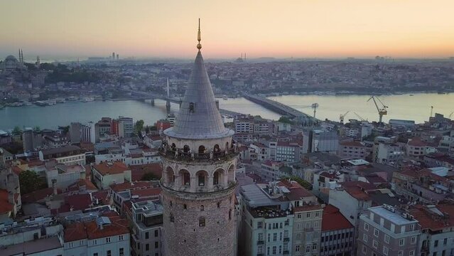 Galata Tower, Istanbul. Sunset over Goldenhorn in the background. Galata, 70 meters height and 16.45m diameter tower build by Byzantium Emperor Anastasius in 507. Drone turns around tower over city
