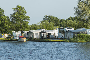 Fototapeta na wymiar camping for motorhomes with large tents on the shore of a lake in the Netherlands