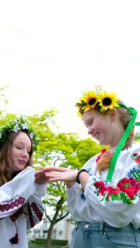 beautiful young women girls weaving wreaths walking laughing chatting in park in garden embroidered national ukrainian shirts wreaths of sunflower flowers and forest white 