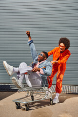 Full length of smiling young african american woman in sunglasses and bright outfit having fun with...