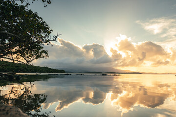Seven seas beach with calm water reflecting the sky during the golden hour with clouds from...