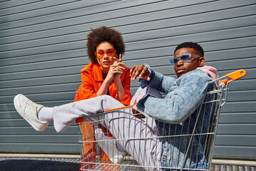 Confident and trendy young african american best friends in sunglasses and bright outfits posing...
