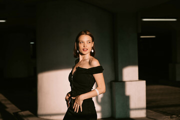 Fototapeta na wymiar sexy attractive woman in black evening dress in sunlight posing. Beautiful elegant woman model beauty standard
