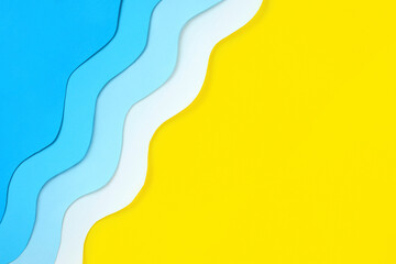 Seaside diagonal background made of color paper. Paper cut blue waves and yellow beach sand with copy space. Summer holidays concept. Relaxation and fun on sea vacations. The ocean coast layout.