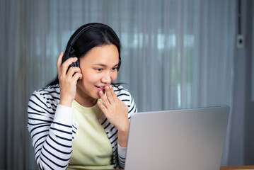 Beautiful woman doing video call on laptop in casual clothing looking surprised