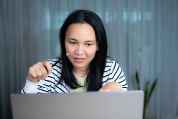 Asian enthusiastic woman in casual clothing working from home on laptop