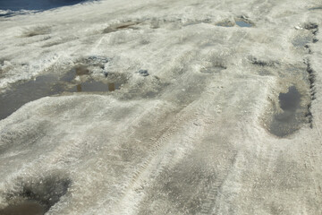 Snow on road. Melted snow on rural road. Winter weather details.