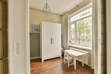 Fototapeta na wymiar a room with wood flooring and white cupboards in front of a window that is open to the outside