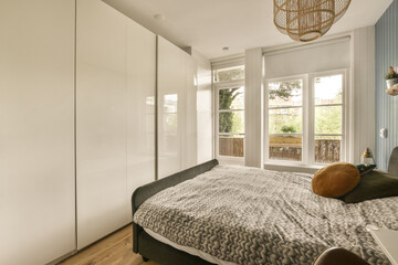 a bedroom with a bed and wardrobes in the corner, next to a window that looks out onto the street