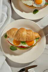 Useful healthy breakfast. Croissant with avocado and eggs on a gray table