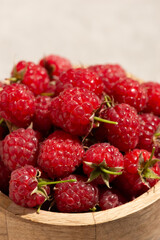 Raspberries in a wooden cup on a gray background. Macro