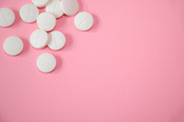 White round pills isolated on pink background with copy space. Focus on the foreground. Pharmaceutical healthcare horizontal concept