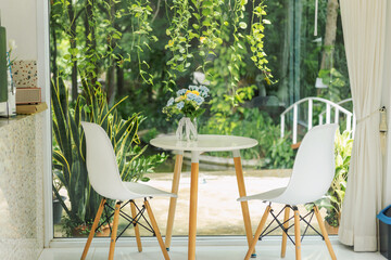 Tables and chairs in a coffee shop There were dried flowers in a vase placed above.