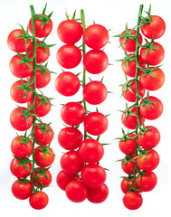 Three red cherry tomatoes on branch with water drops isolated on white background.