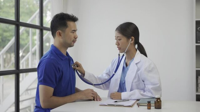 Doctor checking patient's respiratory rate or pulse rate by using stethoscope Asian man patient are checked up his health while a woman doctor use a stethoscope to hear heart rate.