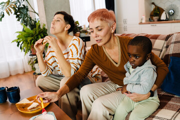 Lesbian couple eating sandwiches while spending time with their son