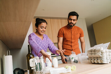 Indian couple sorting rubbish on their kitchen at home