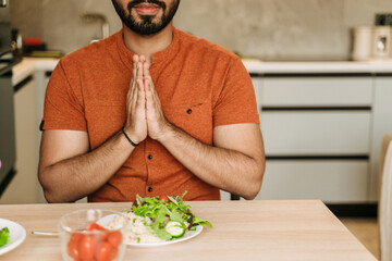 Young indian man praying before lunch at home