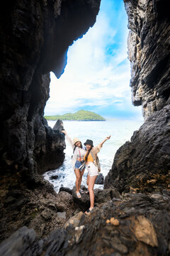 Women traveler enjoy the trip of hiking to the natural cave in the sea, summer moment on trip traveling