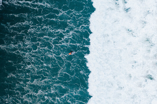Aerial view of a surfer in front of a wave in Famara beach, Lanzarote, Spain.