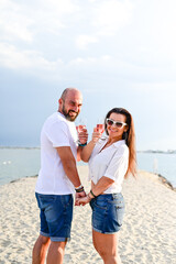  Portrait of a happy Smiling beautiful young couple in while standing at the beach.Happy casual couple holding hands and hugging and walking at the beach 