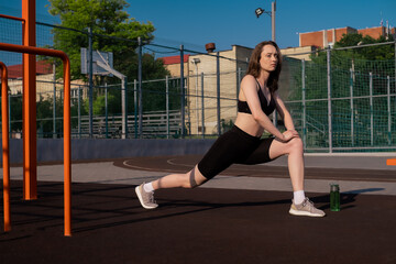 Sports girl doing morning workout and stretching on street sports ground. Fitness training on the sports ground, healthy lifestyle, athletic body