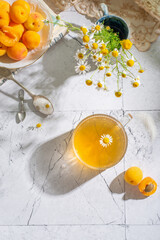 Chamomile tea, apricots and flowers on the light background close up. Top view - 622686762