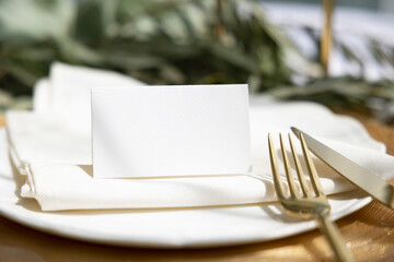 Name card mockup on plate with gold cutlery on olive branch background