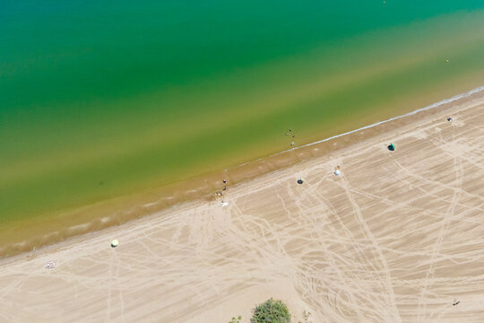 Aerial view of people with parasol on Plaja de Riumar, a beach in Delta de l'Ebre national park, Deltebre, Tarragona, Spain.